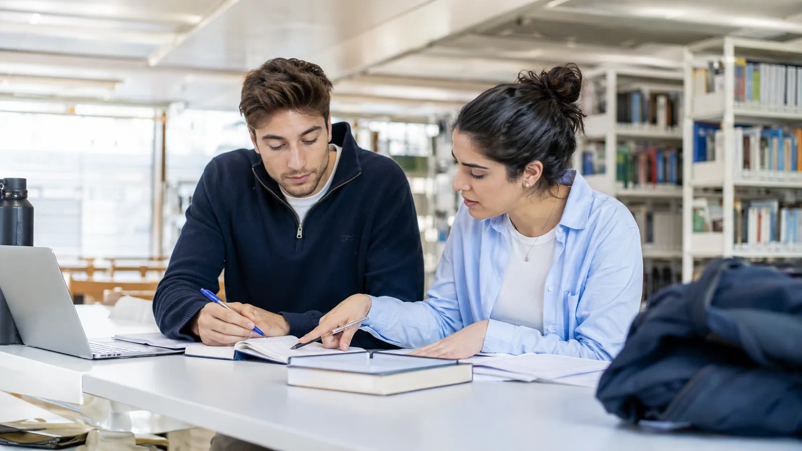 Zwei Studierende prüfen ihren Lern- und Prüfungsplan in der Bibliothek.