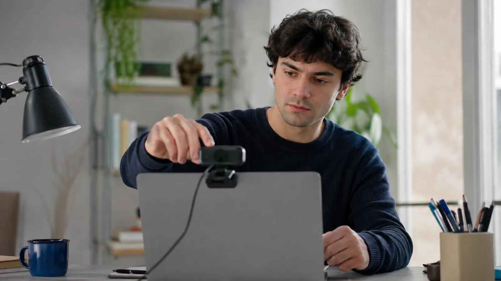 Studieninteressent richtet den Laptop an seinem Schreibtisch für eine Online-Übung aus.